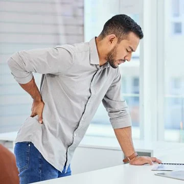 Man With Back Pain Leaning Over Desk